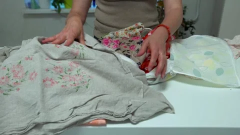 A person arranges various textiles, including floral-patterned fabric and lace, Stock Footage 336068213
