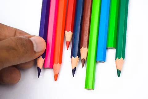 Person arranging some different colored wood pencil crayons on a white backgr Stock Photos
