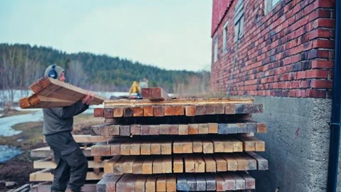 Person Arranging Tall Stack of Squared Timber Outdoors Stock Footage 347689960