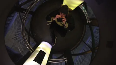 A person ascending in a modern glass elevator, surrounded by soft yellow and pur Stock Footage 296532784