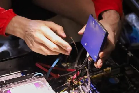 Person assembling computer hardware and blue metal case Stock Photos