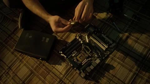 Person assembling computer motherboard on checkered floor Фото
