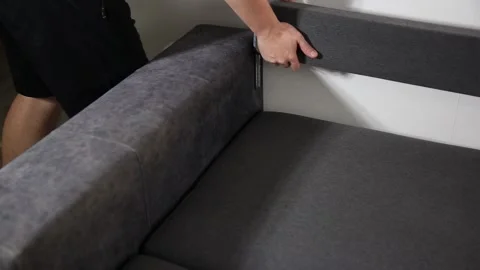 Person assembling contemporary grey sofa, precisely adjusting backrest cushion Stock Footage 329622191