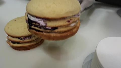 Person assembling a multi-layered sponge cake with cream and blueberry filling o Stock Footage 331778437