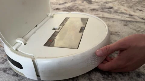 Person assembling or adjusting robot vacuum cleaner on floor at home, smart Video stock 337109535