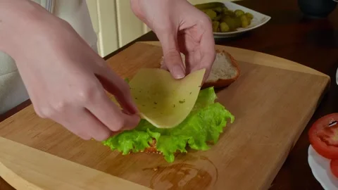 Person assembling sandwich layers lettuce cheese tomato sliced bread 库存影片 345060991