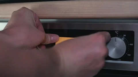A person is attaching a sticky note labeled hot to an oven dial, indicating the Stock-Footage 339096737
