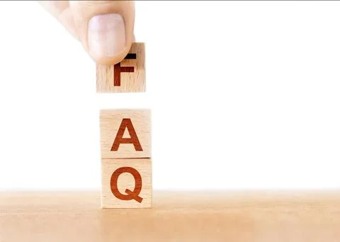 Person attempting to stack a wooden block on top of an FAQ document Stock Photos