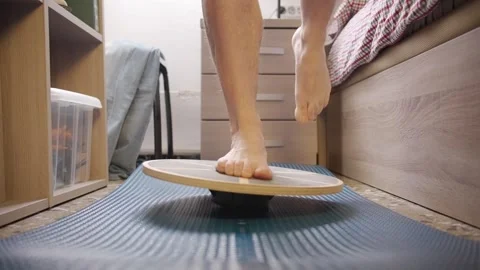 A person balances on one leg using a balance board at home Video stock 270297530