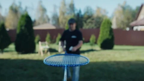 Person balancing badminton racket in backyard Stock Footage 318585205
