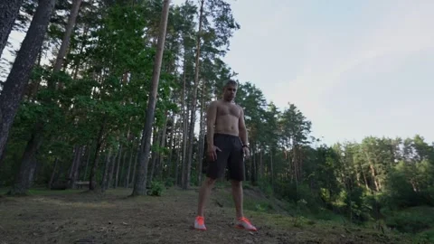 Person with bare torso tilts forward in forest glade Vídeo Stock 196172389