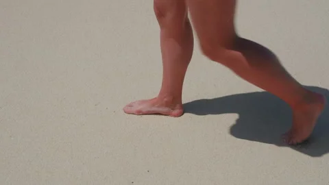 Person barefoot on sandy beach with shadow cast in sunlight Stock Footage 346367104