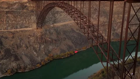 Person base jumping off epic bridge at sunset with red parachute Stockbeeldmateriaal 142916710