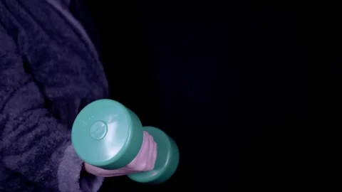 Person In Bathrobe Doing Bicep Curls With Green Dumbbell On Black Background Vídeos de archivo 330176644