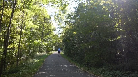 Person bikes down path Stock Footage 74070260