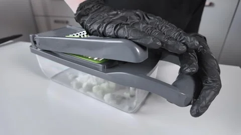 Person in black gloves chops fresh onion with a modern vegetable chopper on.. Stock Footage 322795153