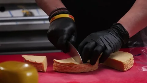 Person in black gloves cutting corn tortillas on a red cutting board Stock Footage 331634636