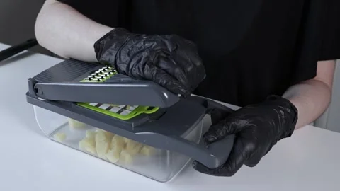 Person in black gloves using a modern kitchen vegetable chopper to dice pee.. Stock Footage 322794955
