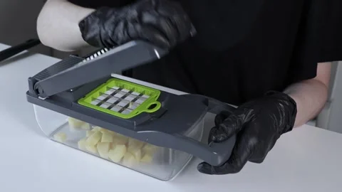 Person in black gloves using a practical manual vegetable chopper to dice a.. Stock Footage 322794982