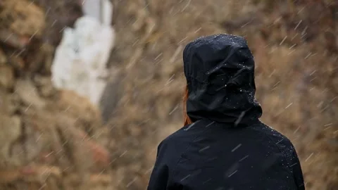 Person in black jacket sitting in falling snow in slow motion Stock Footage 345385403
