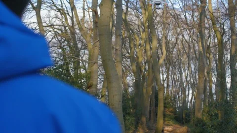 A person in a blue jacket is flying with the drone through the forest Stock Footage 87274048