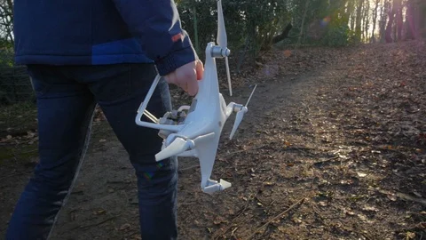 A person in a blue jacket goes with a drone through the forest in slowmotion Stock Footage 87273261