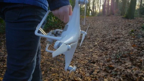 A person in a blue jacket goes with a drone through the forest in slowmotion Stock Footage 87276445