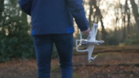A person in a blue jacket goes with a drone through the forest in slowmotion Stock Footage 89959307