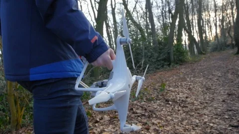 A person in a blue jacket goes with a drone through the forest in slowmotion Stock Footage 89959353