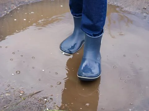 A person in boots standing in a muddy puddle Stock Photos