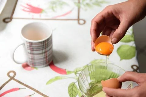 Person breaking an egg shell to separate the yolk from the white. Stock Photos