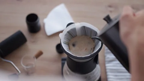 Person brewing drip coffee, pouring water over coffee grounds in paper filter Stock Footage 337401943