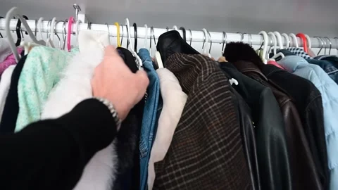Person browsing and choosing clothes hanging in a closet Video stock 325702359