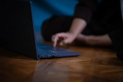 Person browsing internet using laptop on wooden floor 스톡 사진
