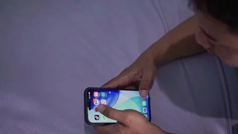 Person browsing phone screen while lying on bed in low light. Stock Footage 340485871