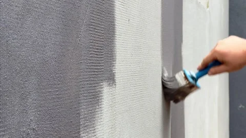 A person is brushing quartz texture onto a wall for an even application Stock Footage 296775814