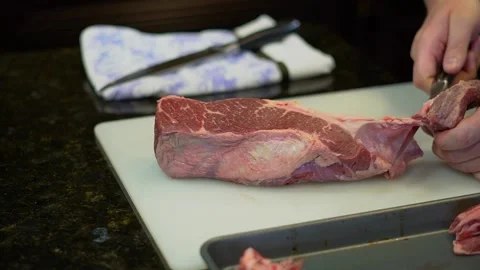 Person butchering beef meat in the kitchen with a knife Video stock 140136734