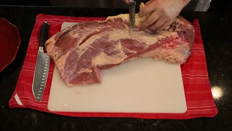 Person butchering beef meat in the kitchen with a knife Stock Footage 141142353