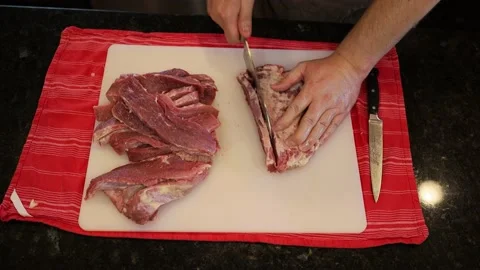 Person butchering beef meat in the kitchen with a knife Stock Footage 141164053