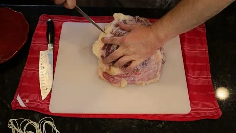 Person butchering beef meat in the kitchen with a knife Stock Footage 141237275