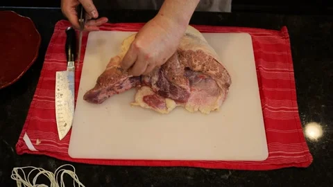 Person butchering beef meat in the kitchen with a knife Stock Footage 141237384