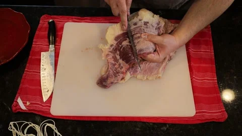 Person butchering beef meat in the kitchen with a knife Video stock 141237385
