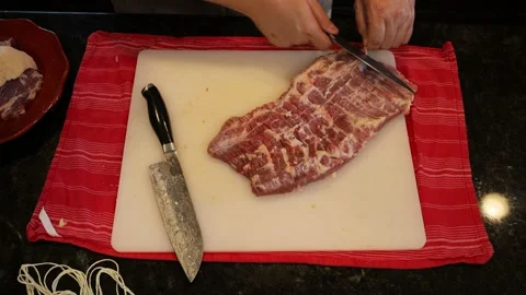Person butchering beef meat in the kitchen with a knife Stock Footage
