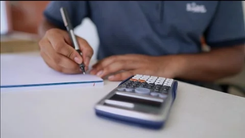 Person Calculating and Writing Notes, Person using a calculator and writing.. Stock Footage 317736988