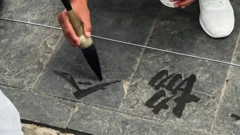 Person calligrapher practicing water calligraphy on stone Stock Footage 339789715