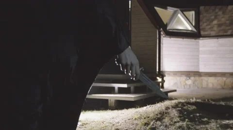 Person in a cape with a knife moving to the house Stock Footage 59377173