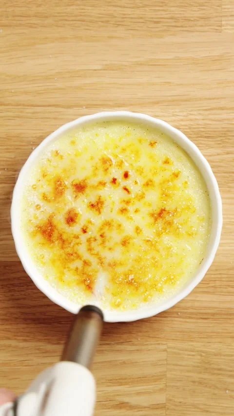 Person caramelizes sugar with kitchen torch over ramekin. Stock Footage 345273915