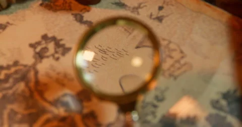 Person carefully examines an ancient map with a magnifying glass, trying to find Stock Footage 197343430