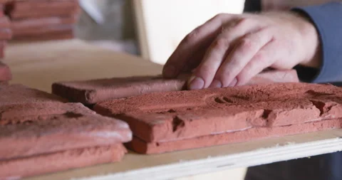 Person carefully puts tile based on casts of old bricks with stamp on shelf of Stock Footage 185796412
