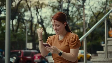 Person celebrating while holding smartphone outdoors Stock Footage 323896928